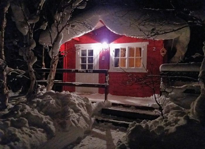 Welcome to Bakkakot Cabins red guesthouse with snow on top near Akureyri Iceland