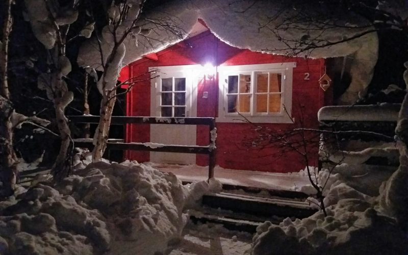 Welcome to Bakkakot Cabins red guesthouse with snow on top near Akureyri Iceland